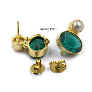 May include: A pair of gold earrings with green gemstone and white pearl accents. The earrings have a post back closure. Earring Post.