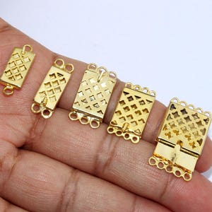 May include: A collection of gold-coloured rectangular jewellery clasps featuring a lattice pattern. Each clasp has multiple loops for attachment. The clasps are shown against a plain background.