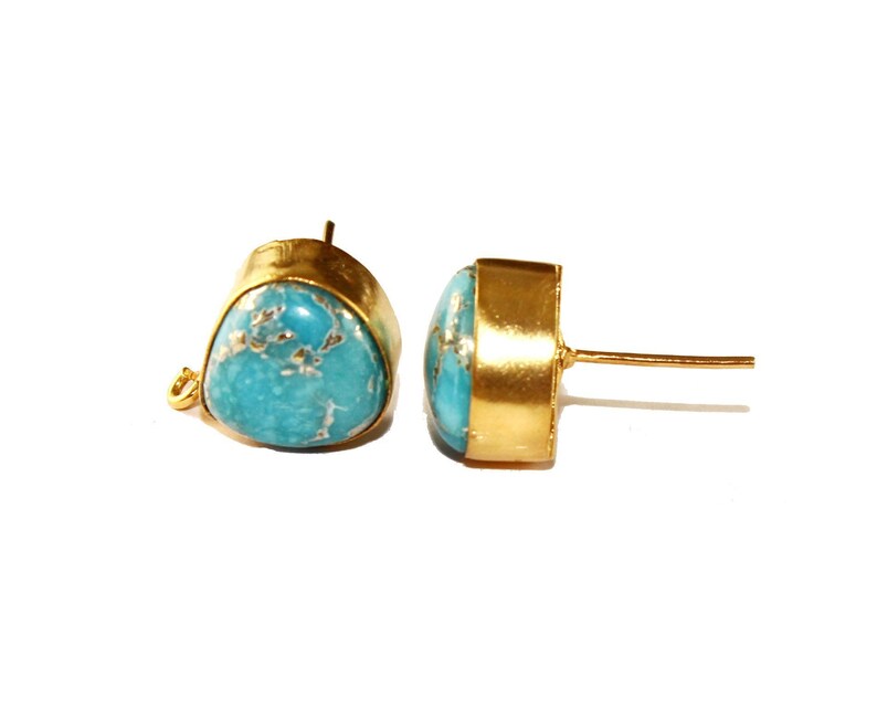 May include: A pair of gold-tone earrings with turquoise stones. The earrings are oval shaped and have a simple design.