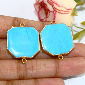 Puede incluir: Dos colgantes de piedra turquesa azul con marcos de metal dorado y anillos de salto. Los colgantes son de forma octogonal.