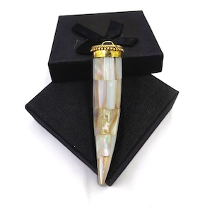 May include: A white and gold pendant shaped like a tooth, made of mother of pearl and gold. The pendant is in a black box.