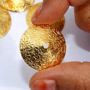 May include: Gold-toned metal embellishments with a floral design and a hole in the center.