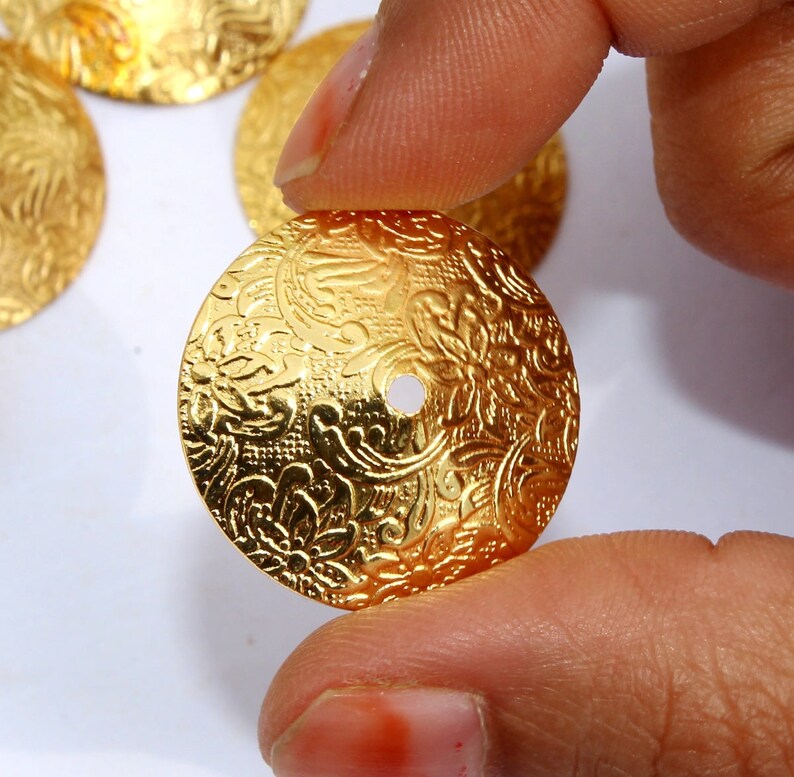 May include: Gold-toned metal embellishments with a floral design and a hole in the center.