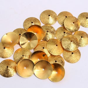 May include: A collection of gold-colored metal embellishments with a textured surface. The embellishments are shaped like small, shallow bowls.