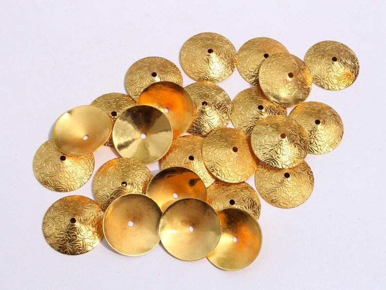 May include: A collection of gold-colored metal embellishments with a textured surface. The embellishments are shaped like small, shallow bowls.