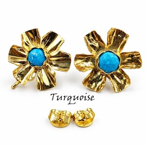 May include: A pair of gold-toned flower-shaped stud earrings featuring a central round turquoise stone. The petals have a textured, hammered finish. The word Turquoise is printed below the earrings, accompanied by two gold-toned earring backs.