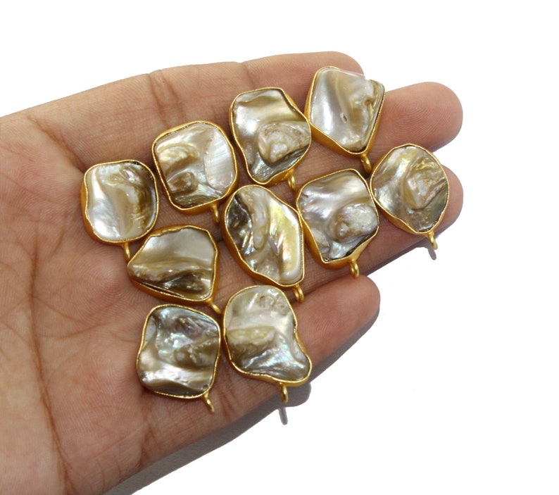 May include: Ten gold-toned metal charms with a pearlescent finish. Each charm has a different shape and features a unique pattern.