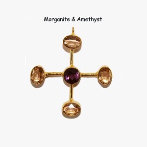 Puede incluir: Colgante dorado con dise&ntilde;o de cruz. La piedra central es una amatista morada oscura, rodeada de cuatro piedras de morganita ovaladas. El texto "Morganite & Amethyst" est&aacute; encima del colgante. Joya.