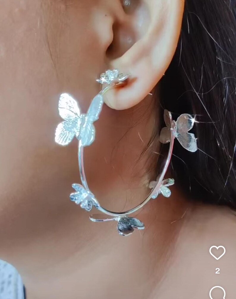 Puede incluir: Pendientes de aro plateados con dise&ntilde;o de mariposa. Los pendientes est&aacute;n hechos de metal y tienen un acabado pulido.