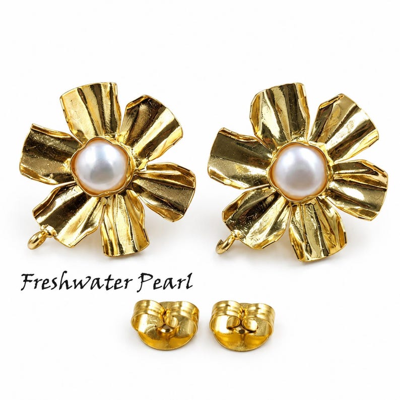 May include: A pair of gold-toned flower-shaped earrings featuring a central white freshwater pearl. Each earring has a textured, petal-like design and a small loop at the bottom. Two matching gold-toned earring backs are included below the earrings.