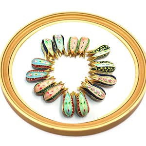 May include: A collection of 12 colorful, hand-painted teardrop-shaped pendants with gold accents. The pendants are arranged in a circle on a white background.