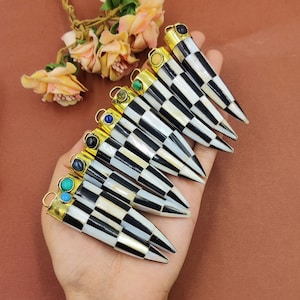 May include: A set of eight black and white checkerboard patterned bone pendants with gold accents and colorful gemstone accents.