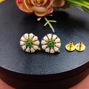 Puede incluir: Un par de pendientes de oro con un diseño de flor de perla blanca y piedra preciosa verde. Los pendientes tienen un cierre de poste.