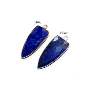 May include: Two lapis lazuli pendants, one with a gold setting and one with a silver setting. The pendants are shaped like a pointed oval and have a faceted surface.
