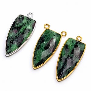 May include: Three teardrop-shaped pendants featuring faceted green and black stone with magenta inclusions. One pendant is set in a silver-toned metal frame with a single top loop, while two pendants are set in gold-toned metal frames with dual top loops.