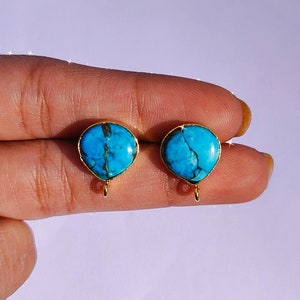May include: A pair of gold earrings with turquoise stones. The stones are a light blue color with brown veins running through them.
