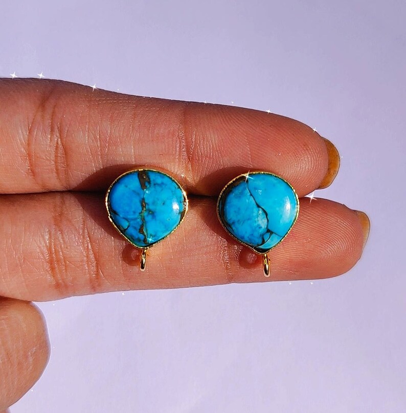 May include: A pair of gold earrings with turquoise stones. The stones are a light blue color with brown veins running through them.