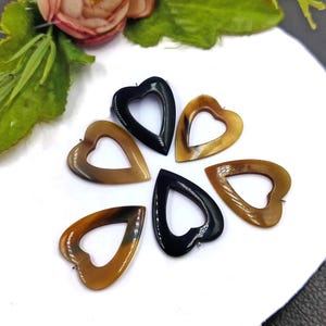 以下が含まれることがあります： 角で作られた6つのハート型のペンダント。ペンダントは茶色と黒の2色です。ペンダントの上部に紐を通すための穴があります。