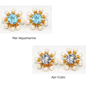 Peut inclure: Deux paires de boucles d'oreilles avec un sertissage en or et un cercle de perles entourant une pierre pr&eacute;cieuse. La premi&egrave;re paire pr&eacute;sente une pierre d'aquamarine bleu clair. La deuxi&egrave;me paire pr&eacute;sente une pierre de zircone cubique transparente. Le texte "Mar-Aquamarine" et "Apr-Cubic" se trouve sous les boucles d'oreilles.
