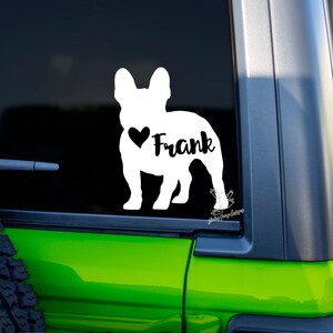 Puede incluir: Calcoman&iacute;a de vinilo blanco con la silueta de un Bulldog Franc&eacute;s con un coraz&oacute;n y el nombre "Frank" en la ventana de un coche verde.