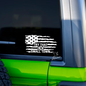 May include: A white vinyl decal with a distressed American flag design and the text "TRY THAT IN A SMALL TOWN".