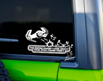 Puede incluir: Una pegatina de vinilo blanco en un coche verde. La pegatina muestra un caza TIE de Star Wars volando sobre figuras de palo. El texto dice "El Imperio no se preocupa por tu familia de figuras de palo."