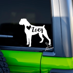 May include: White vinyl decal of a boxer dog silhouette with a heart and the name "Zoey" on a black car window.