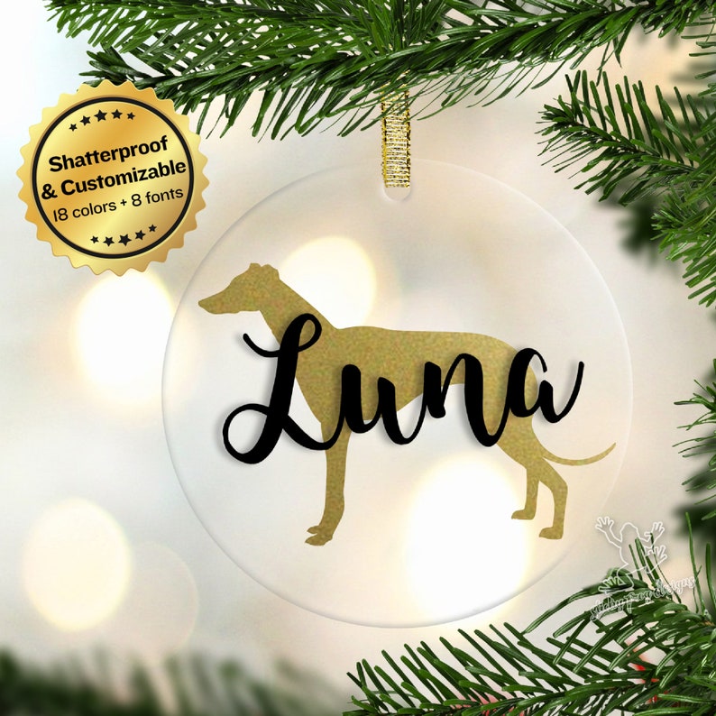 May include: A clear glass Christmas ornament with a gold glitter Greyhound silhouette and the name "Luna" in black script.