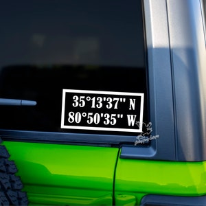 May include: A white sticker with black text on a green car. The sticker reads "35°13'37" N 80°50'35" W".