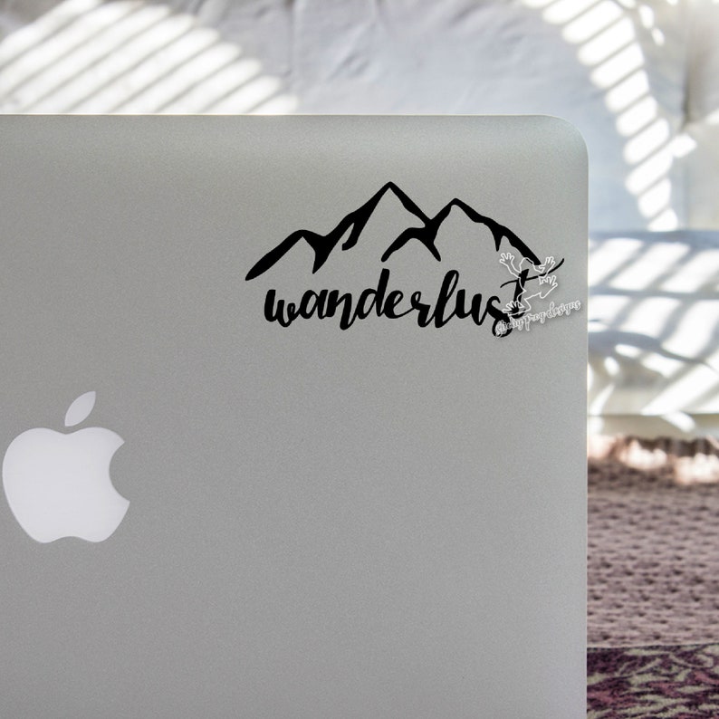 May include: A black and white sticker with a mountain range silhouette and the word "wanderlust" in cursive script.