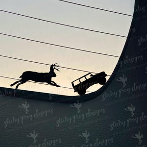 May include: Black silhouette of a deer leaping over a line, with a jeep climbing a slope. The background is a gradient of light and dark, with diagonal lines. The text "Sticky Frog Designs" is visible.
