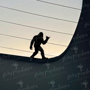 May include: A black silhouette of Bigfoot, giving a "hang loose" hand gesture, is set against a gradient sky. The figure is walking on a curved surface with horizontal lines above. The background has a textured appearance.