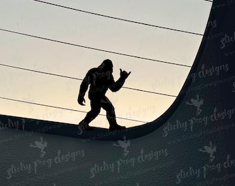 May include: A black silhouette of Bigfoot, giving a "hang loose" hand gesture, is set against a gradient sky. The figure is walking on a curved surface with horizontal lines above. The background has a textured appearance.