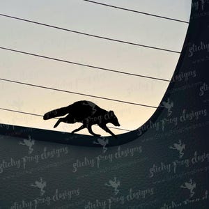 May include: A black silhouette of a running animal, possibly a raccoon or similar mammal, against a backdrop of horizontal lines and a gradient sky. The image has a minimalist design.