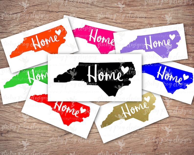 May include: A set of ten North Carolina state outline decals in various colors, including red, green, blue, purple, black, and gold. Each decal features the word "Home" in white with a small heart next to it.