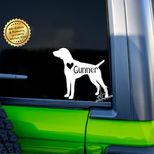 May include: White silhouette of a German Shorthaired Pointer dog with a heart and the name "Gunner" printed on the side. The decal is on a black background.
