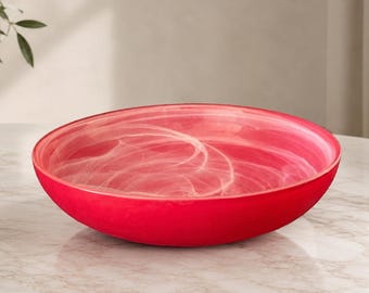 Könnte beinhalten: Eine leuchtend rote dekorative Schale mit glatter Außenseite und einem wirbelnden weißen Muster im Inneren. Die Schale ist rund und steht auf einer Marmoroberfläche. Diese dekorative Schale ist perfekt für die Inneneinrichtung.