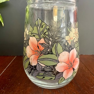 Puede incluir: Un tarro de vidrio transparente con un dise&ntilde;o floral. El dise&ntilde;o presenta flores rosas y naranjas con hojas verdes sobre un fondo negro.