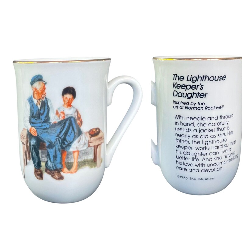 May include: A white ceramic mug with a gold rim featuring an illustration of an older person and a younger person sitting on a bench. The reverse side displays the text: The Lighthouse Keeper's Daughter, inspired by the art of Norman Rockwell.
