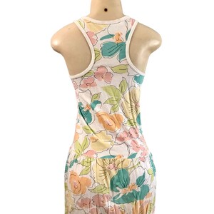 May include: White tank top dress with a floral pattern in pastel colors. The dress features a racerback design with a white trim. The floral print includes pink, yellow, and teal flowers with green leaves, creating a summery look.