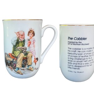 May include: A white ceramic mug with a gold rim featuring a Norman Rockwell illustration of a cobbler working on a shoe with two children nearby. The reverse side displays the text The Cobbler inspired by the art of Norman Rockwell and 1986.