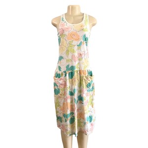 May include: A sleeveless floral dress with a white background. The dress features a scoop neck and two front pockets. The floral pattern includes pink, yellow, and teal flowers. The dress is displayed on a mannequin.