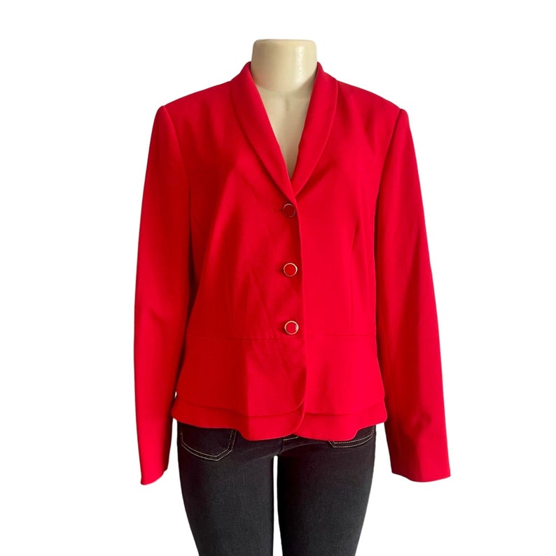 May include: A red blazer with a notched collar and three gold buttons. The blazer has long sleeves and a fitted silhouette. The blazer is displayed on a mannequin against a white background.