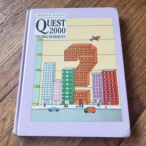 May include: A purple book with the title "QUEST 2000 EXPLORING MATHEMATICS" and a colorful illustration of a city skyline with buildings and a plane flying overhead.