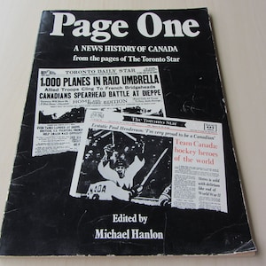 May include: A black and white book cover with the title "Page One: A News History of Canada from the pages of The Toronto Star". The cover features black and white newspaper clippings from The Toronto Star, including a headline about 1,000 planes in a raid umbrella and a photo of a hockey player.