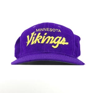 Puede incluir: Gorra de béisbol morada con la inscripción amarilla "Minnesota Vikings". La gorra tiene una visera curva y una corona estructurada. Un accesorio deportivo para los aficionados.