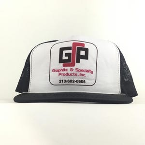 Puede incluir: Una gorra tipo trucker blanca y negra con un logotipo en el panel frontal que dice GSP, Graphite & Specialty Products, Inc., y el número de teléfono 213/602-0606. La gorra tiene una visera negra y paneles laterales y traseros de malla.