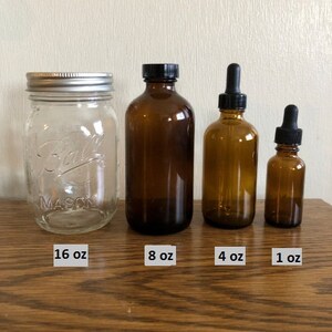 May include: Four glass bottles of different sizes with black lids. The bottles are labeled with their volume: 16 oz, 8 oz, 4 oz, and 1 oz.