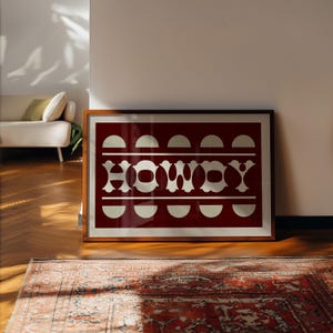 May include: A framed print with a red background and white geometric design. The design features the word "HOMME" in a stylized font.