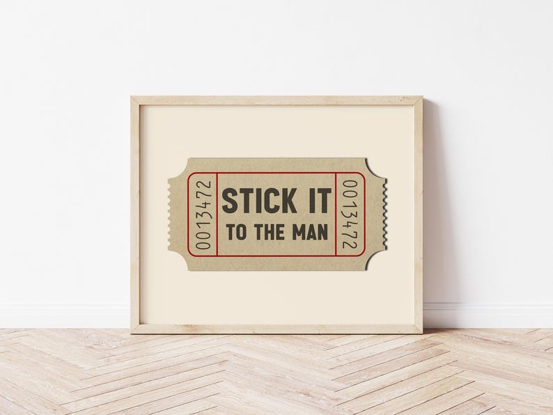 May include: A framed print of a vintage ticket with the text "STICK IT TO THE MAN" printed in black on a brown background. The ticket number 0013472 is printed on both sides of the ticket.
